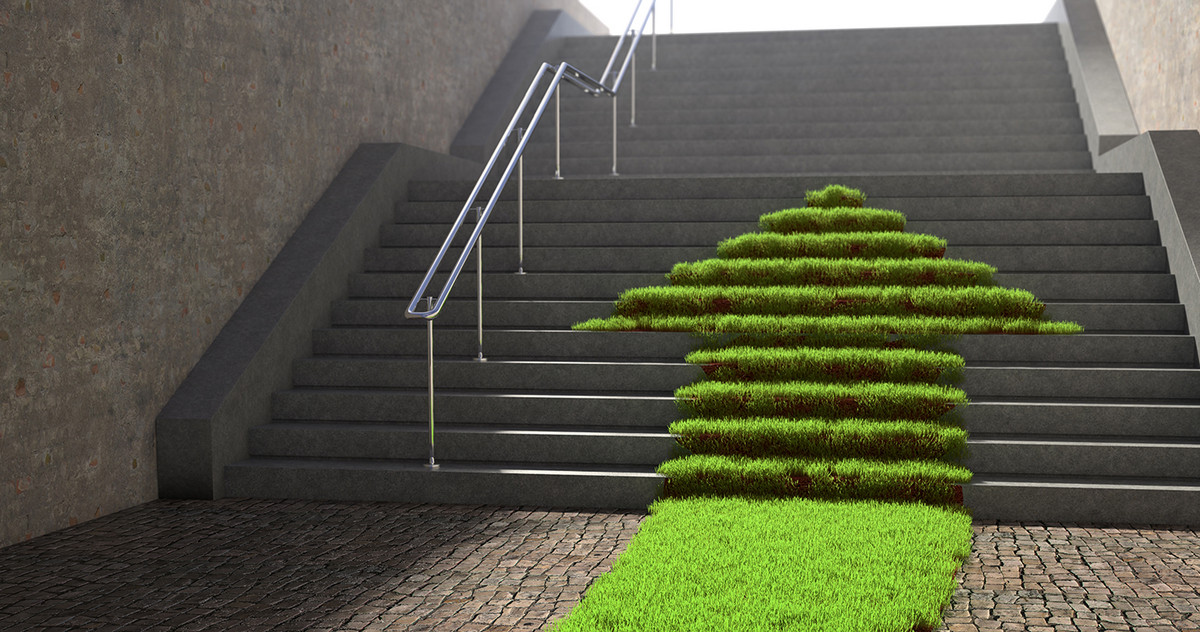 A green arrow made of grass moves up a flight of concrete stairs