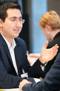 A young man in business attire talking to someone