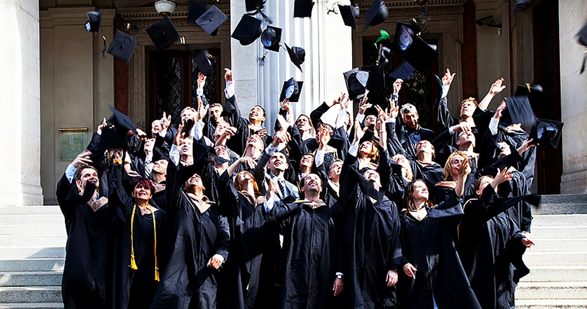 Graduates throw their graduation hats in the air.