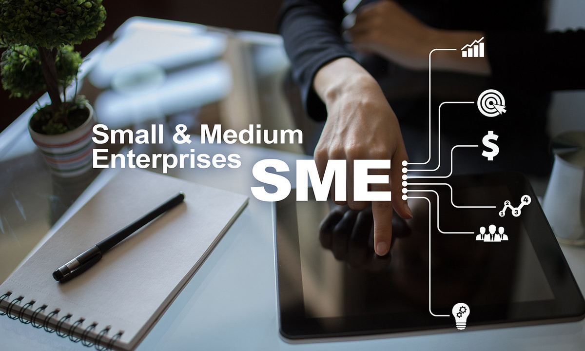 Ein Tablet auf das mit einem Finger gezeigt wird, daneben ein Block mit Stift. Über das gesamte Bild steht "Small & Medium Enterprises SME"