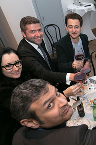 3 men and a lady at dinner, smiling at the camera