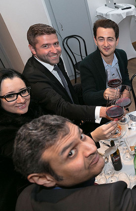 3 men and a lady at dinner, smiling at the camera