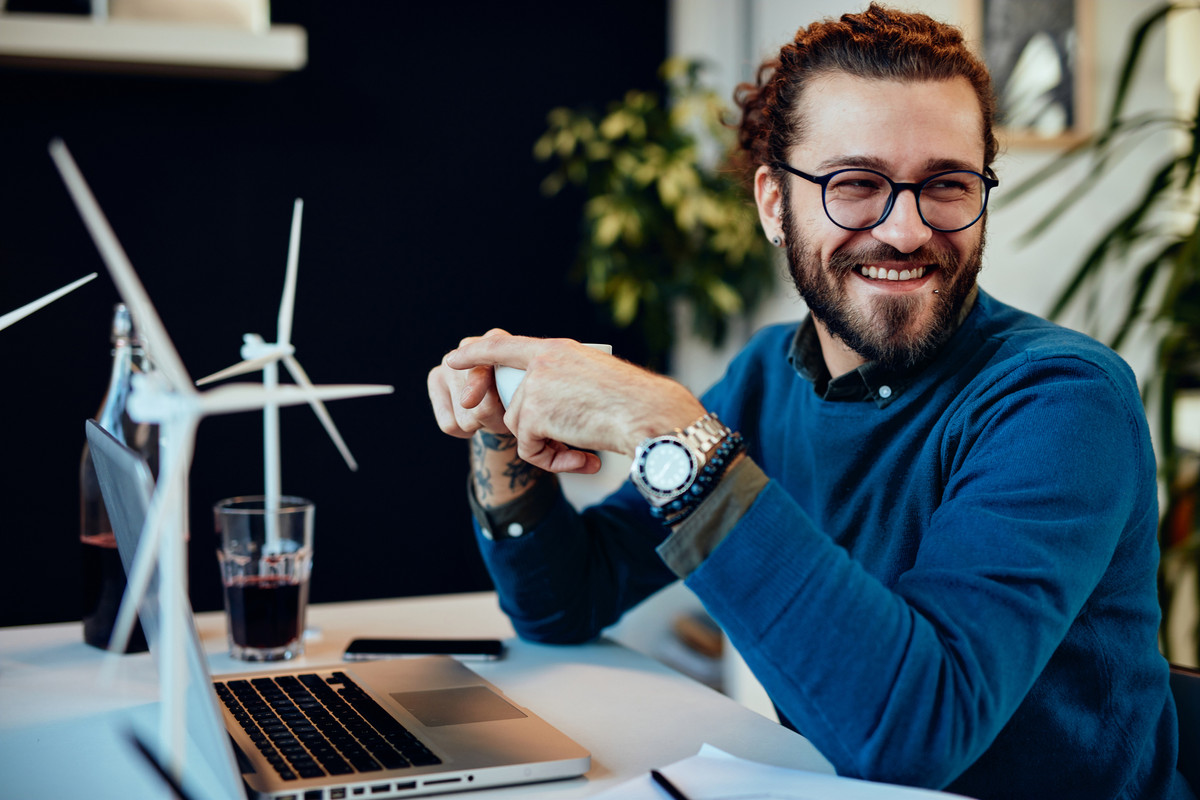 A man in front of a laptop with small models of wind turbines on his table