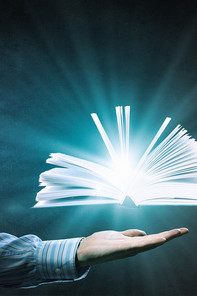 a bright glowing book floating above an open hand