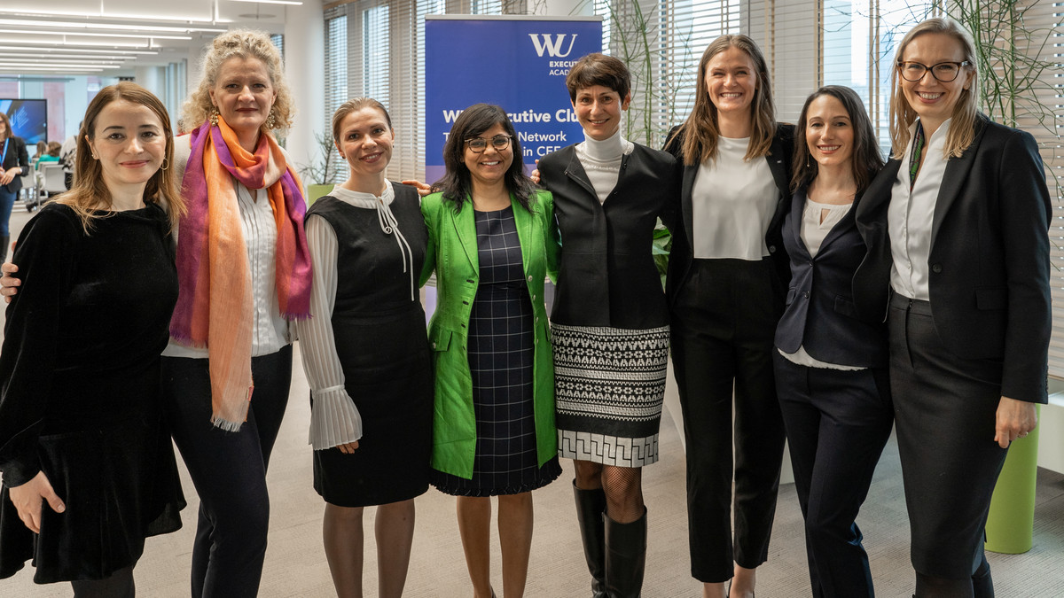 Die Damen des Female Leaders Network stehen Arm in Arm vor einem Banner der WU Executive Academy
