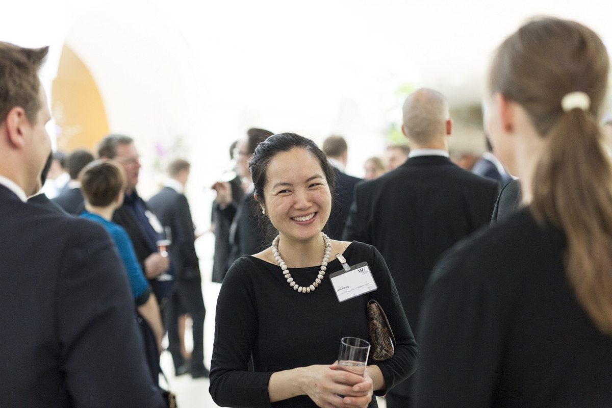 A smiling asian businesswoman talking to people during a business event