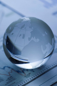 A glass globe of the world resting on some business sheets