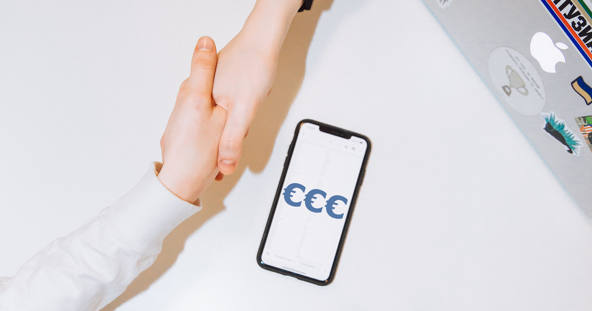 Two people shake hands, next to them is a smartphone with 3 big euro signs on it