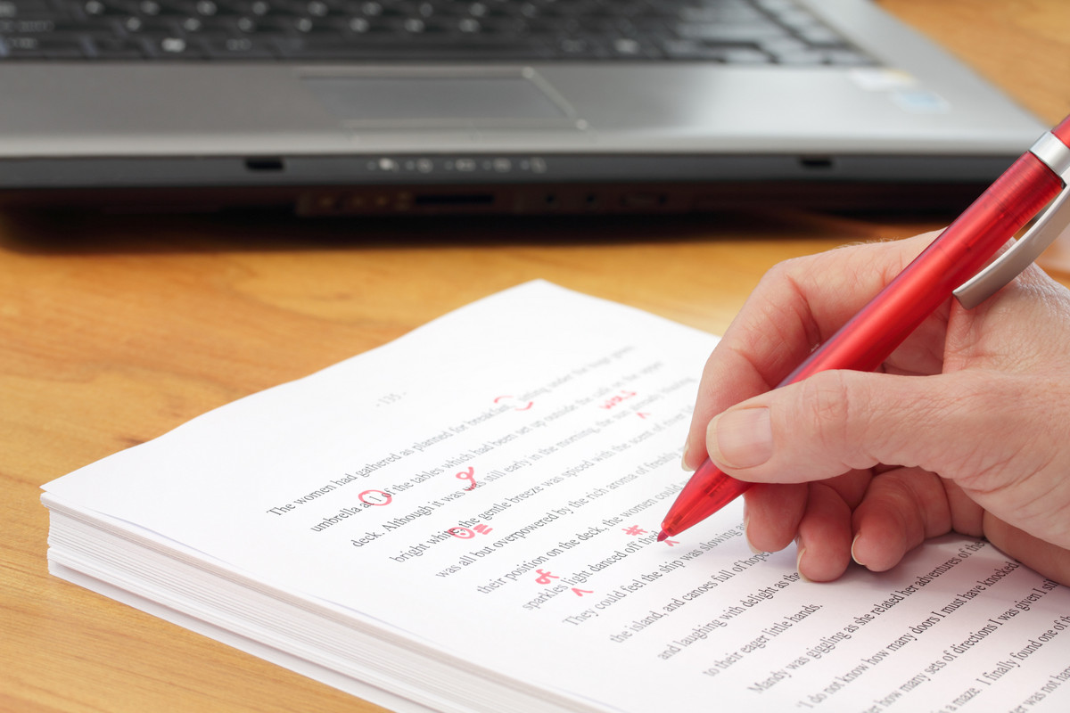 Editor with red pen proofreading a document