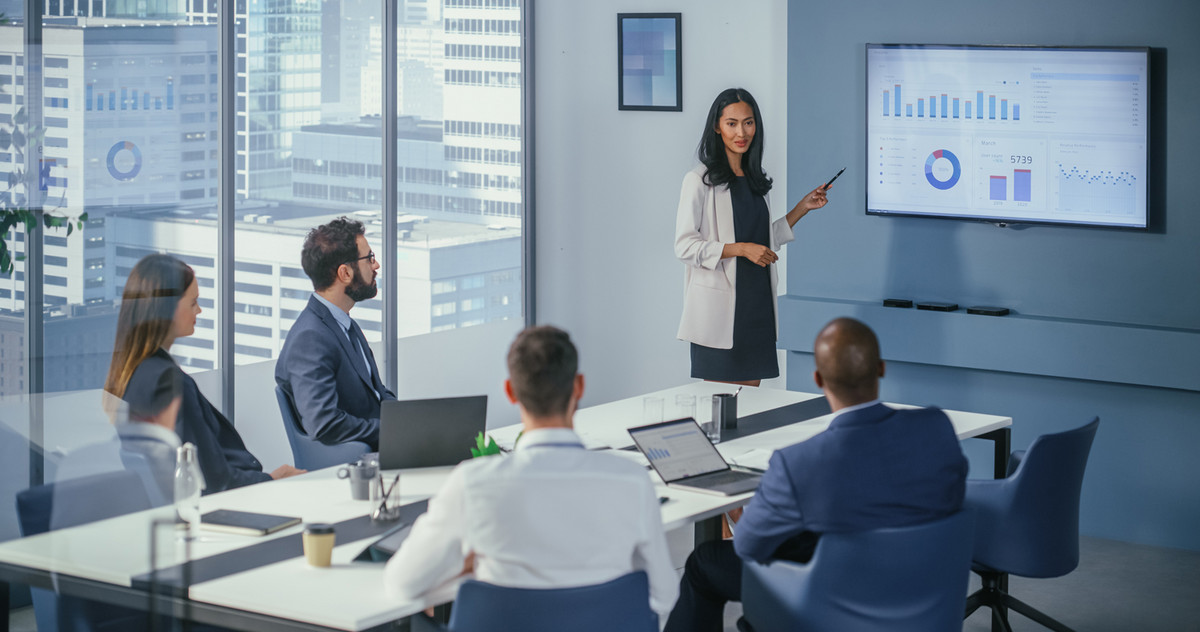 The language of stakeholders - one of the most important CFO skills is communication - if nobody knows what you're talking about, you won't be taken seriously. Image: shutterstock, Gorodenkoff - A woman stands in front of a display and explains the numbers to four listeners