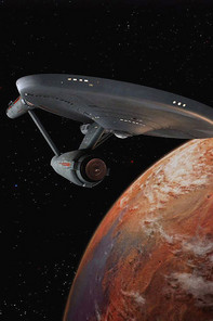 Starship Enterprise flies past a planet
