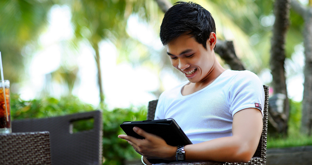 Ein Mann lacht bei der Benutzung eines Tablets