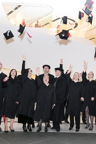 Studierende werfen freudig Ihre Graduierungshüte in die Luft