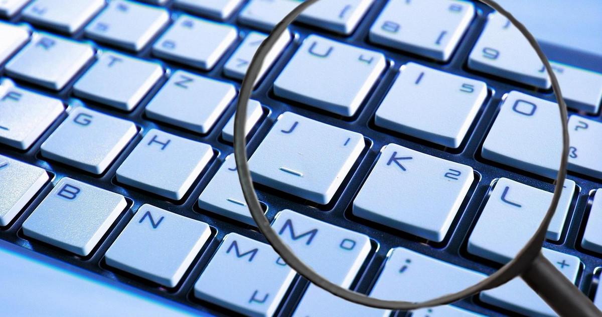 pic of a keyboard with a magnifying glass, symbolyzing focus on cyber security