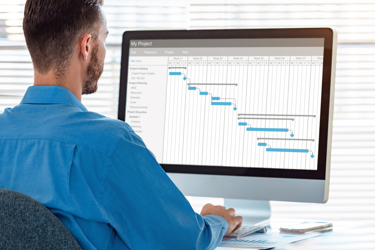 A business man sitting in front of his monitor working on a GANTT sheet