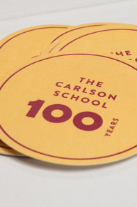 A golden coin with "100 years Carlson University" written on it in red