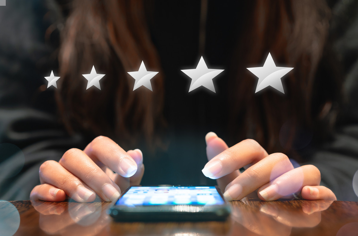 A smartphone lying on a table, with 5 rating stars hovering above it